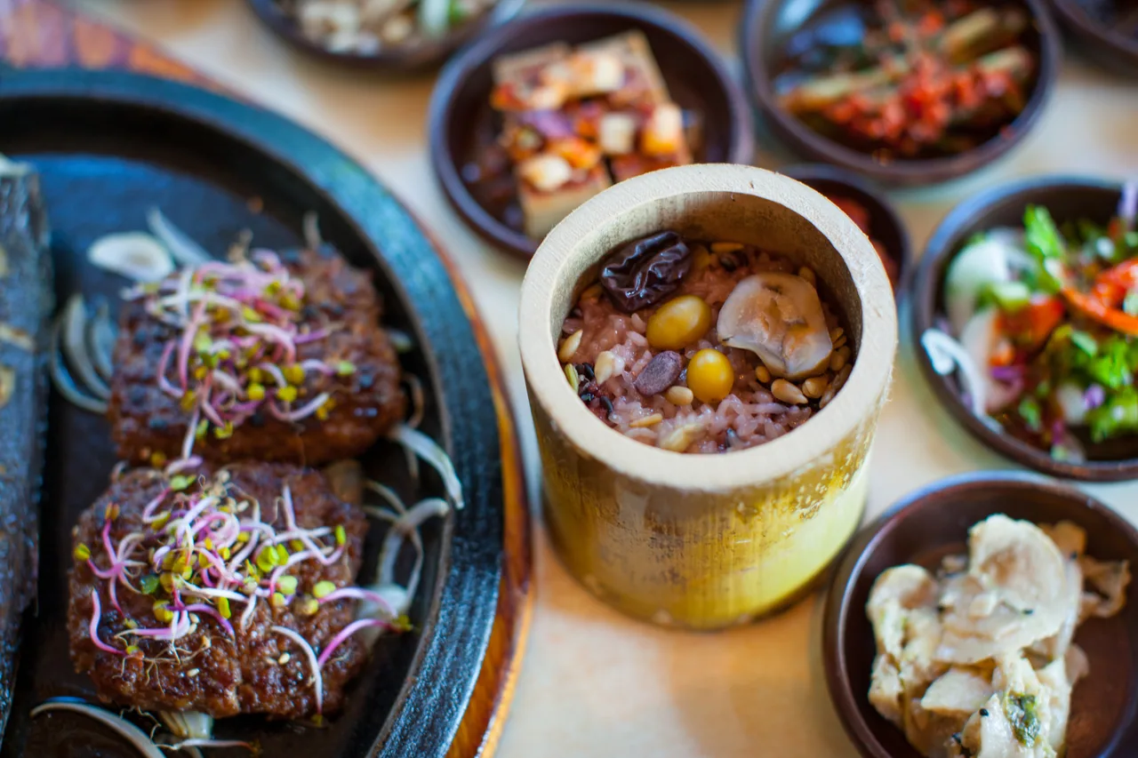 A neatly set table with steaming bamboo-tube rice and Damyang tteokgalbi